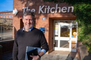 Man with folder standing outside kitchen symbolizing innovative founder-teams