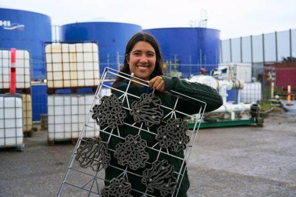 Woman holding metal piece, related to Danish marine startups in biodiversity project